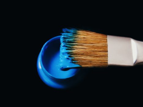 Malerpensel med blå maling på sort baggrund